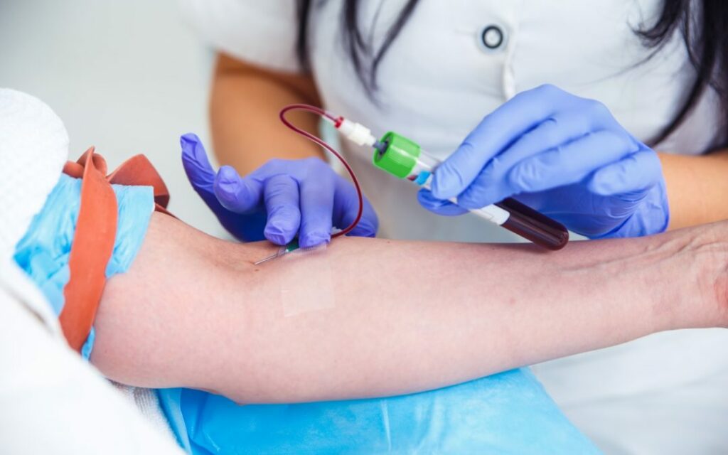 Hands of a phlebotomist extracting blood samples from a patient for medical testing.