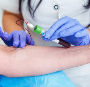 Hands of a phlebotomist extracting blood samples from a patient for medical testing.